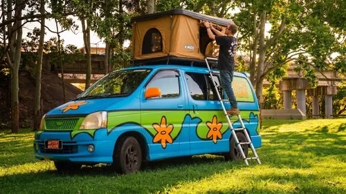 Campervan Village painted campervan with a rooftop tent parked in a park